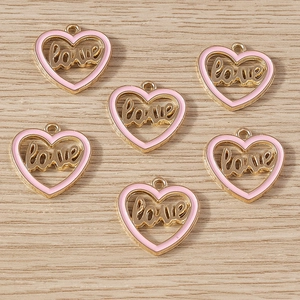 Detailed macro view of six gold-plated pink heart charms with love cutout for DIY jewelry