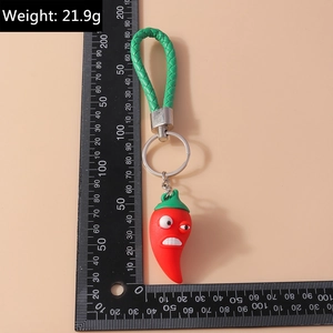 Détail d'un porte-clés piment rouge avec lanière en cuir vert et règle de mesure latérale