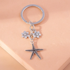 Detail of silver starfish and flower pendant charms on a minimalist metal keychain