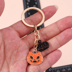 Halloween pumpkin cat keychain with golden ring and black cutout charm on hand