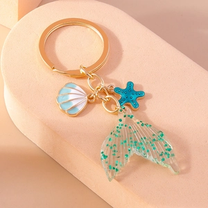 Detail of mermaid tail keychain with teal sequins, blue starfish, and shell charms