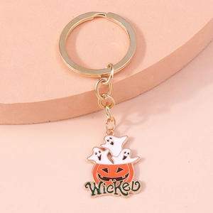 Detailed close-up of a Halloween pumpkin and ghost keychain with Wicked text on gold metal