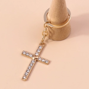 Detailed macro view of a gold cross keychain featuring sparkling rhinestones and a heart center