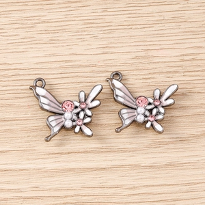 Détail d'un pendentif papillon en alliage avec émail blanc et strass roses pour le DIY