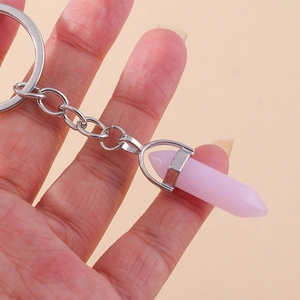 Close-up of a pink hexagonal crystal bullet pendant on a silver metal keychain ring