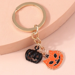 Detail of Halloween keychain with black pumpkin and orange cat-faced enamel charms on gold ring