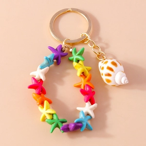 Close-up of golden keychain with colorful starfish charms and realistic seashell pendant