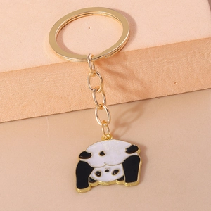 Nahaufnahme von goldenem Schlüsselanhänger mit zwei Emaille-Pandas auf rosa Hintergrund