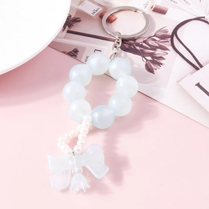 Detail of beaded keychain with blue iridescent pearls and translucent ribbon bow pendant