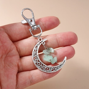 Ethnic crescent moon keychain featuring silver filigree design and light green stone beads