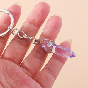 Detail showing hand holding a purple crystal hexagonal pillar keychain with silver link chain
