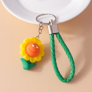 Détail de porte-clés tournesol avec breloque en PVC, sangle en cuir vert et anneau argent