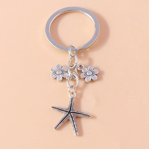 Macro shot of silver alloy starfish and floral charms on a metallic keyring pendant