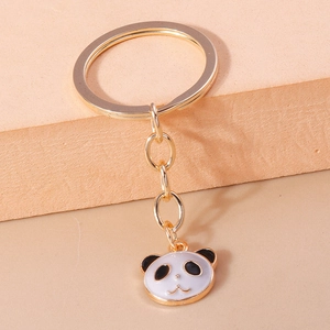Nahaufnahme von Panda-Schlüsselanhänger aus Goldmetall mit Emaille-Gesicht auf Podest