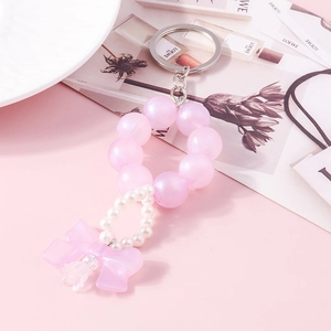 Detailed close-up of pink beaded keychain featuring a frosted bow and pearl accents