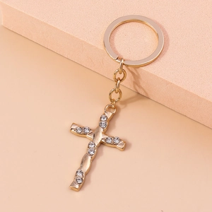 Macro detail of golden cross keychain featuring sparkling rhinestones and twisted metal craft