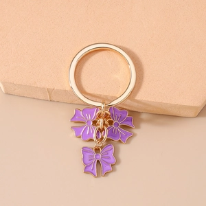 Detailed close-up of golden keychain with purple enamel flowers and bow charms