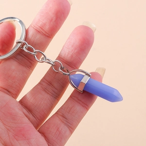 Detail of a purple hexagonal crystal bullet keychain held in hand with silver chain