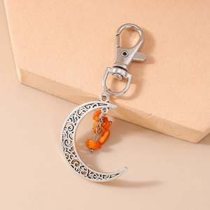 Detailed macro view of crescent moon keychain with silver scrollwork and orange stone beads