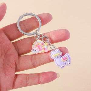 Cute rainbow and purple alpaca keychain held in hand for size comparison