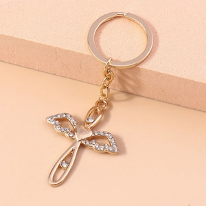 Close-up of golden Christian cross keychain with sparkling rhinestones and angel wings