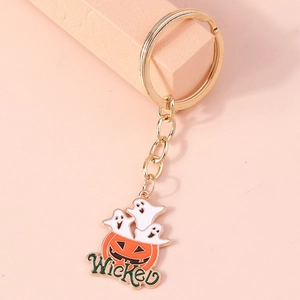 Detail of Halloween keychain with orange pumpkin and white ghosts on gold metal