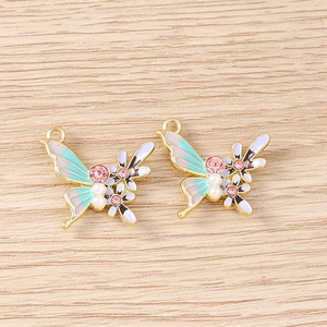 Détail des pendentifs papillon en émail coloré avec strass roses et perles blanches