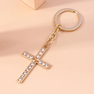 Macro detail of a gold cross keychain with sparkling rhinestones and a heart center