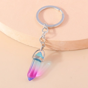 Close-up of a gradient crystal hexagonal pillar keychain on a beige geometric prop