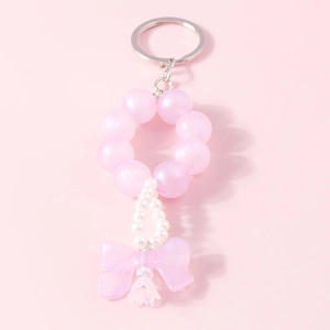 Detail of pink beaded bow keychain featuring elegant faux pearls and acrylic charms