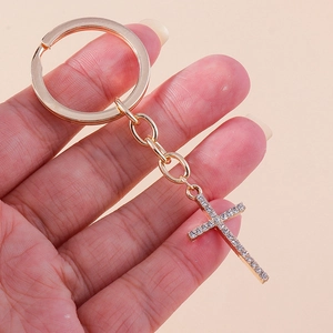 Detailed close-up of a golden keychain featuring a cross pendant encrusted with rhinestones