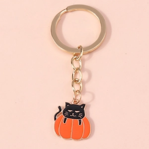 Close-up of a black cat inside an orange pumpkin keychain with a golden metal ring