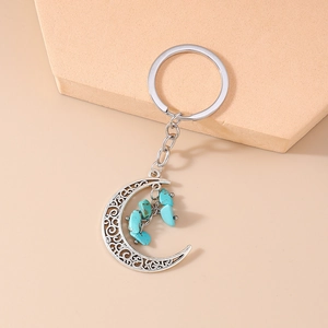 Close-up of vintage hollow crescent moon keychain with blue turquoise stone details