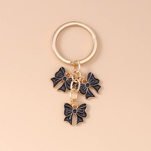 Detailed macro view of triple black bow pendants with golden edges on a metal keychain