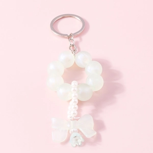 Detailed view of elegant pearl beaded keychain featuring a delicate bow and floral pendant