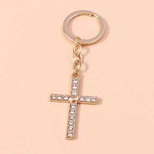 Macro detail of golden cross keychain with heart center and pavé set crystal rhinestones