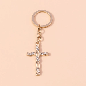 Macro detail of golden cross keychain featuring twisted texture and sparkling rhinestones