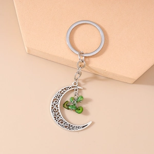 Detail of ethnic crescent moon keychain with hollow design and green stone charms