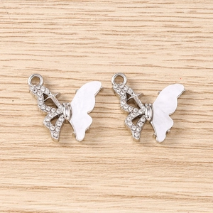 Détail de pendentifs papillons argentés avec strass et détails en nacre blanche
