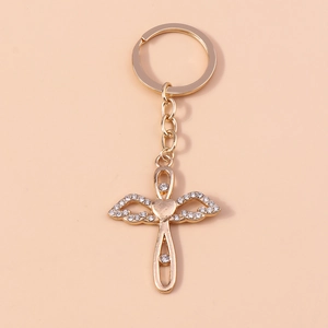 Close-up of golden angel wing cross keychain with sparkling rhinestones and a heart charm