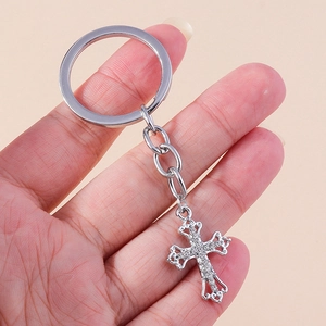 Close-up of silver christian cross keychain with sparkling rhinestones and hollow engraving
