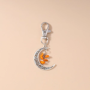 Detail of silver crescent moon keychain featuring orange turquoise stones and lobster clasp