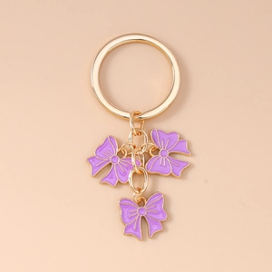 Detail showing gold key ring with three purple enamel bow pendants and high-gloss finish