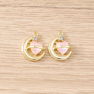 Détail macro de deux pendentifs lune dorés avec cristaux de cœur rose et strass fins