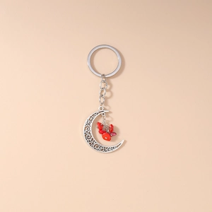 Detail of ethnic hollow crescent moon keychain with vibrant red turquoise stones