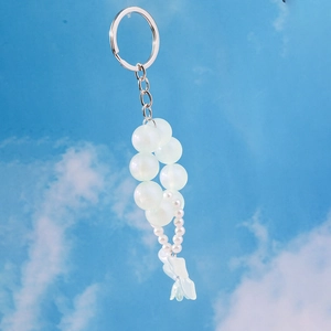 Detail of pearlescent beaded keychain featuring white pearls and translucent petal charm