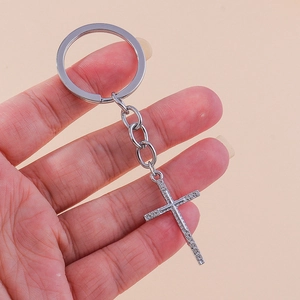 Close-up of a silver-tone cross keychain with sparkling rhinestones held in hand