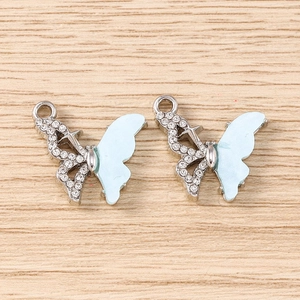 Détail de pendentifs papillon argentés avec émail bleu et strass pour la création de bijoux