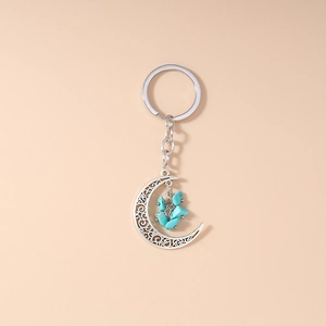 Close-up of bohemian hollow crescent moon keychain with blue turquoise crushed stones