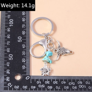 Detail of bohemian cow skull keychain with turquoise stone and floral charms, 14.1g weight